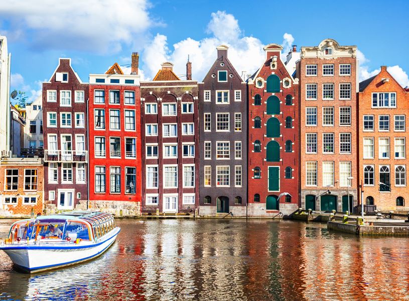 Canal cruise passes colourful houses in Amsterdam, Netherlands