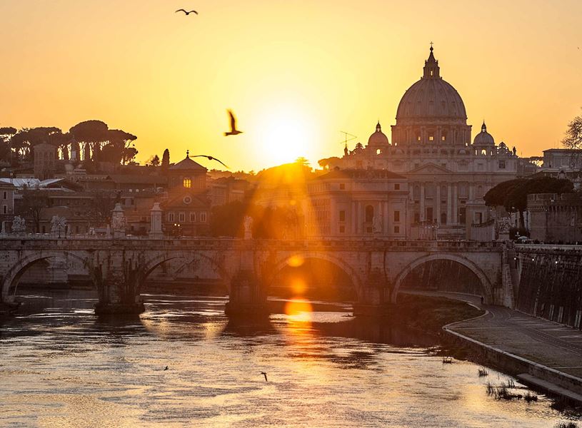 Sunset view of St. Peter’s Basilica with Tiber River and bridge in Vatican City