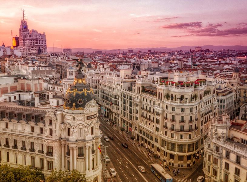 Aerial view of Gran Vía with historic buildings and Metropolis dome at sunset in Madrid