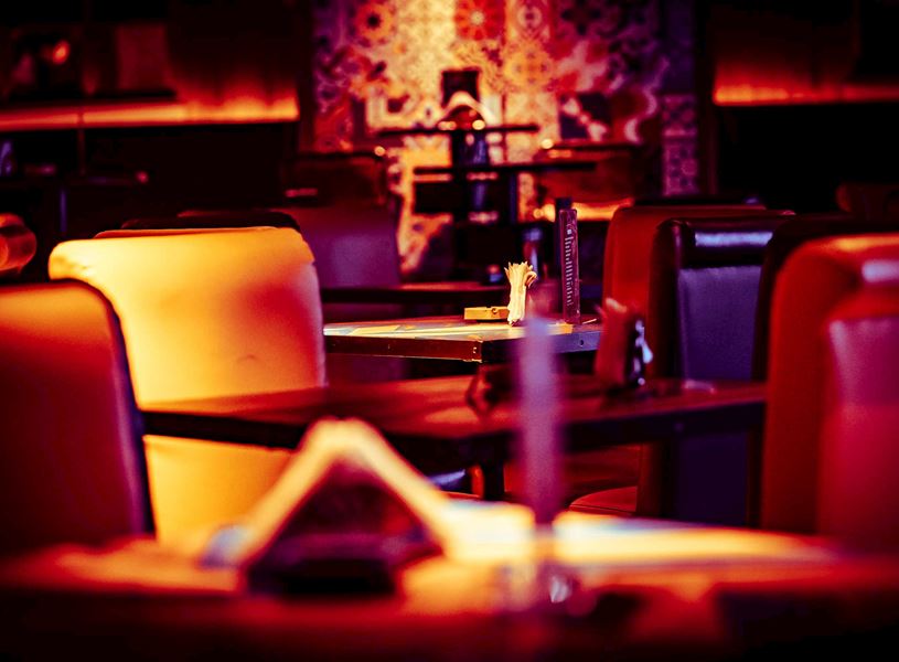 Red seating, warm lighting and neatly set tables
