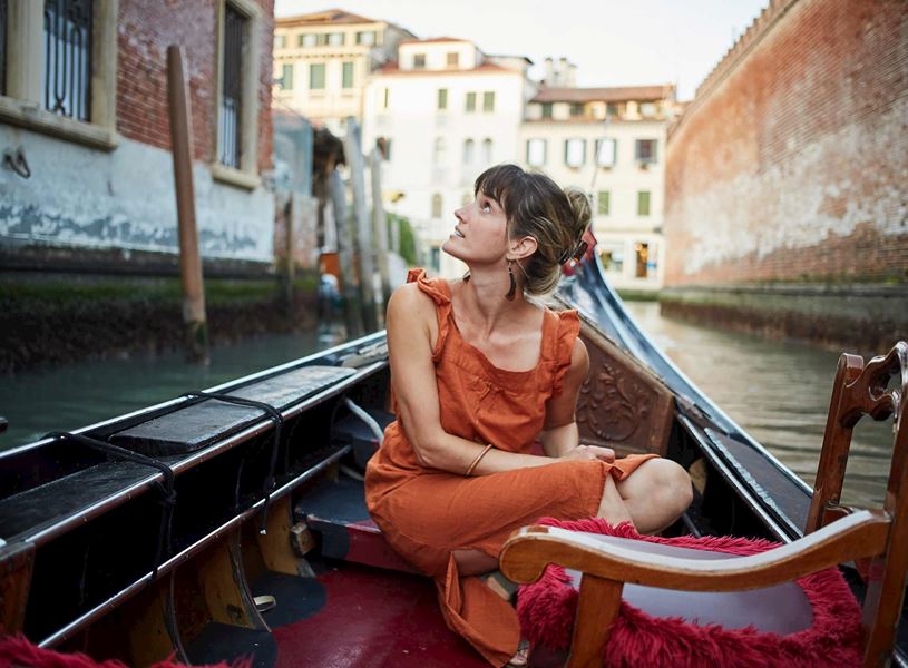 Traveller seated inside gondola on Venetian canal in Venice, Italy