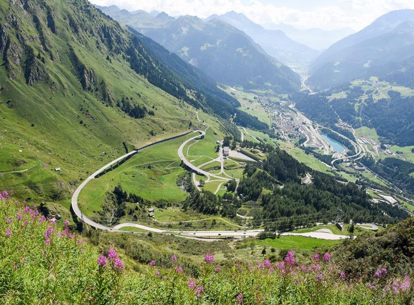 Winding mountain road through lush green valley near Gotthard Pass, Switzerland